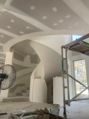 Plasterer rendering a curved staircase feature mid-construction